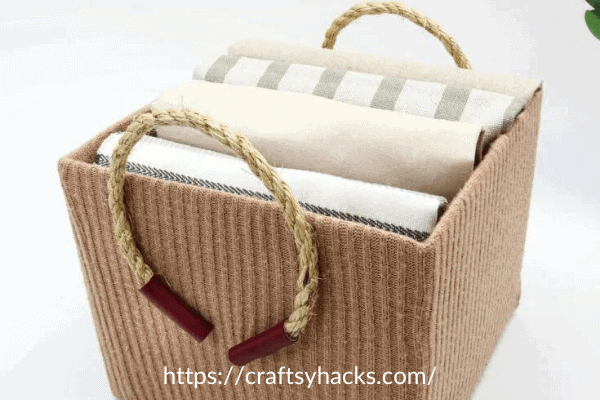 beige storage box made out of a sweater with rope handles
