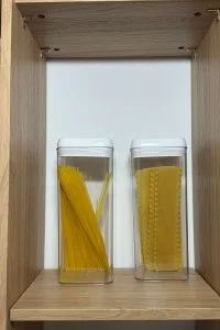 Pasta stored in clear containers in pantry